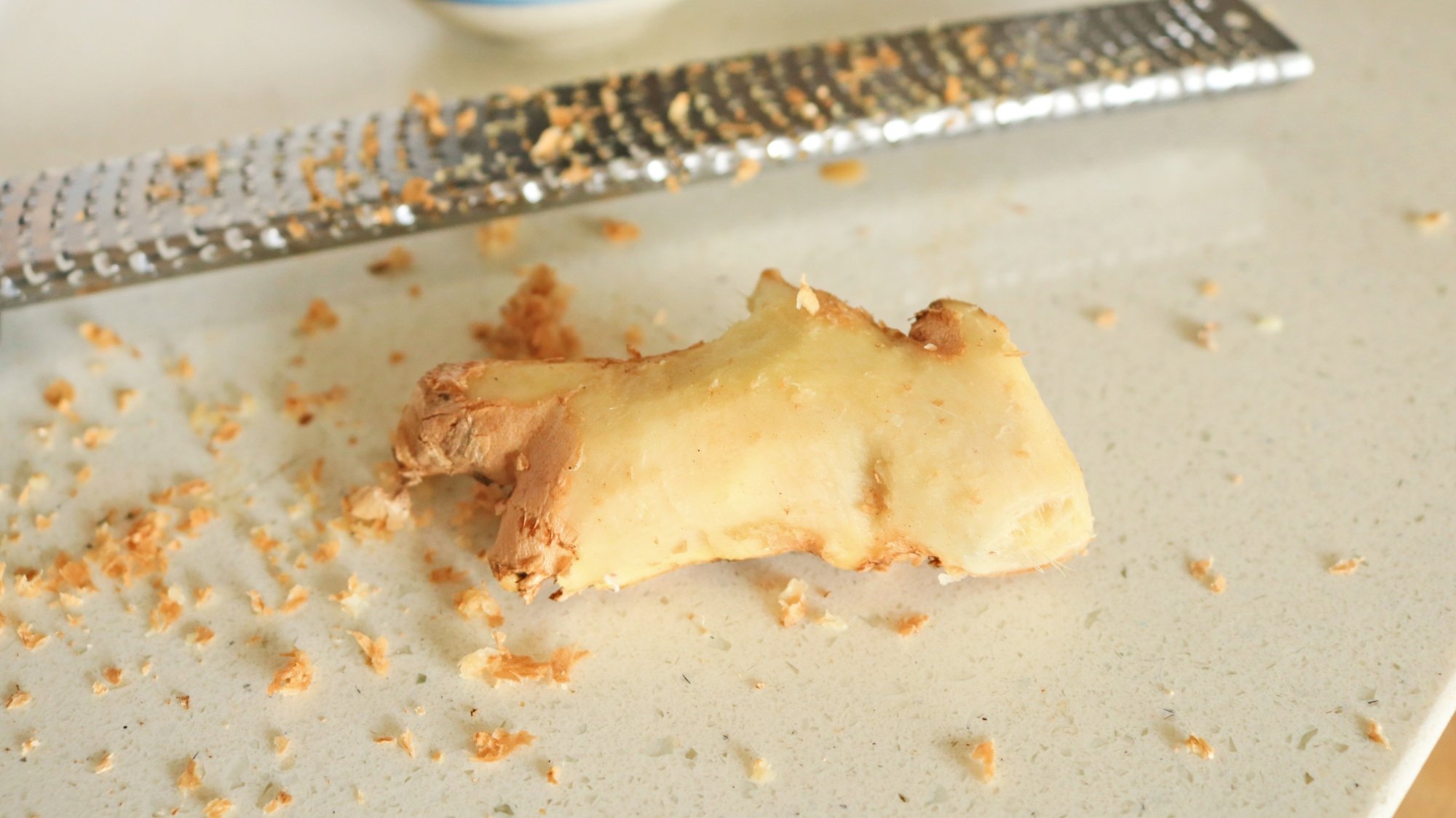 Ginger partially peeled next to a microplane.