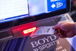 Close-up of a hand taking a receipt-like piece of paper from a. Boyd Sports machine. Boyd Gaming reaches $1 billion revenues in Q3, report states