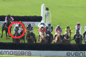 BHA judicial panel hits Kitts and Higgins with major bans in Hillsin betting scandal. A group of jockeys on horses jump a fence during a race on a grassy track. One horse and rider in white and red silks are highlighted with a red circle in the foreground.