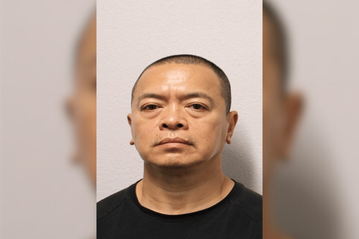A man with a shaved haircut and neutral expression stands against a plain light-colored wall, looking directly at the camera in a mugshot-style photo.