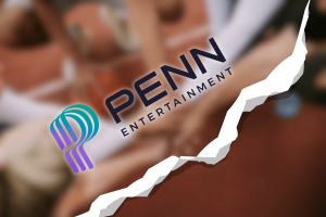 Inside PENN’s costly quest to turn flashy partnerships into market dominance as it ends ESPN deal. A stylized graphic showing the PENN Entertainment logo centered over a blurred background of people placing their hands together. A jagged white tear effect runs diagonally across the image, creating a visual impression of a split or breakup.