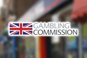 UK posts massive $22B in gambling industry earnings. Gambling Commission logo on top of blurred image of betting shop