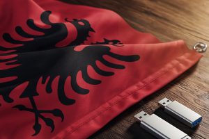 An Albanian flag and two USB drives on a table. Former intelligence chief and son convicted for illegal gambling and state secrets charges in Albania