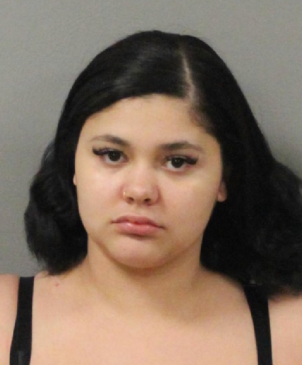 Mugshot-style photo of a woman identified as Naushka Machuca, with dark shoulder-length hair, neutral expression, and a light-colored background.