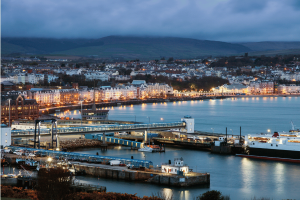 Isle of Man regulator fines gambling operator $273K over AML failures. Isle of Man cityscape in the evening near the harbor